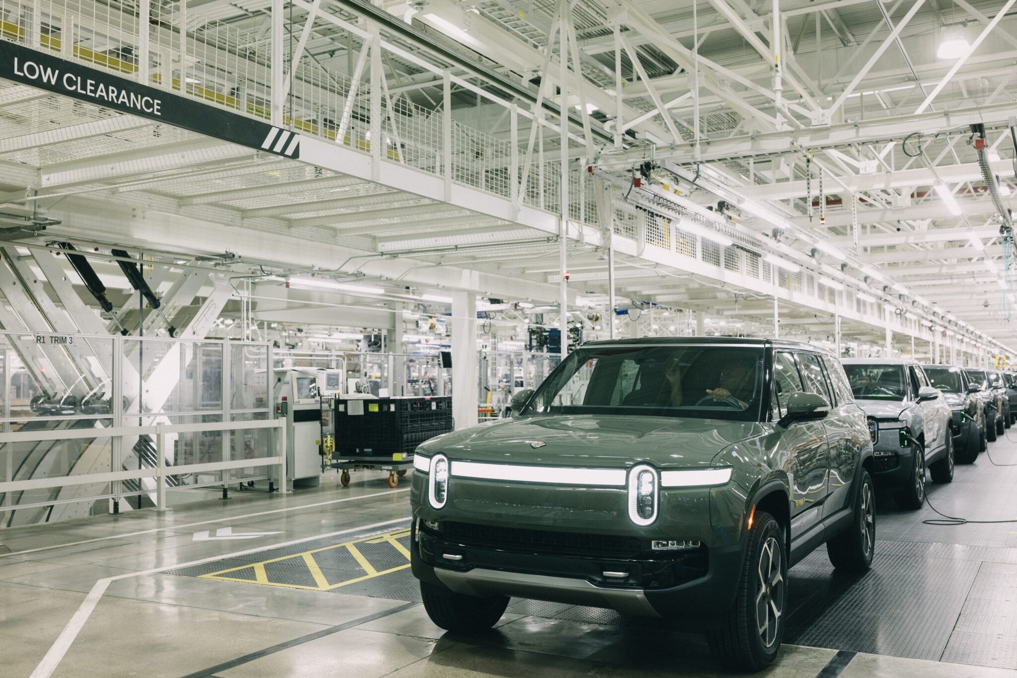 Row of Rivian electric vehicles lined up at company manufacturing facility ready for delivery