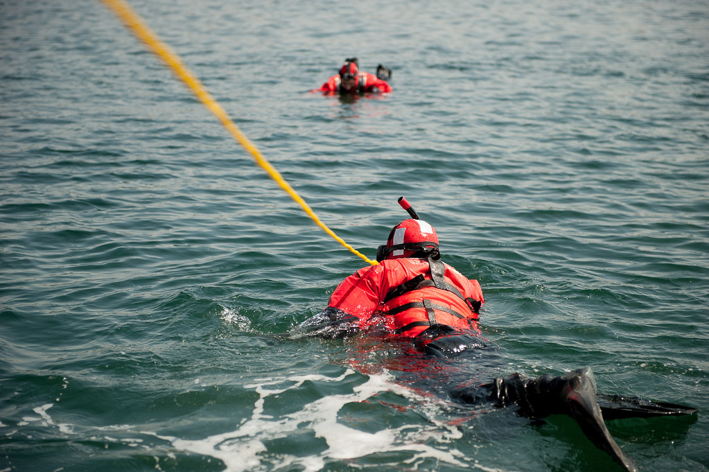 Emergency rescue boats and swimmers conducting water rescue operation beneath bridge spans on river