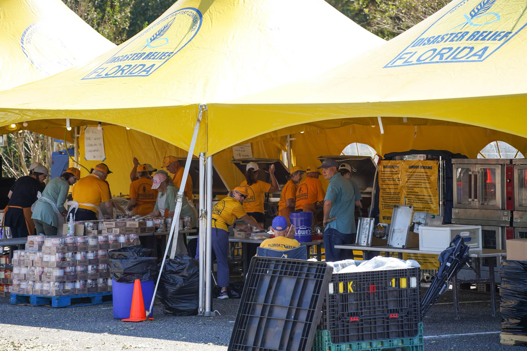 Disaster relief tents set up in church parking lot with volunteers preparing meals for hurricane survivors