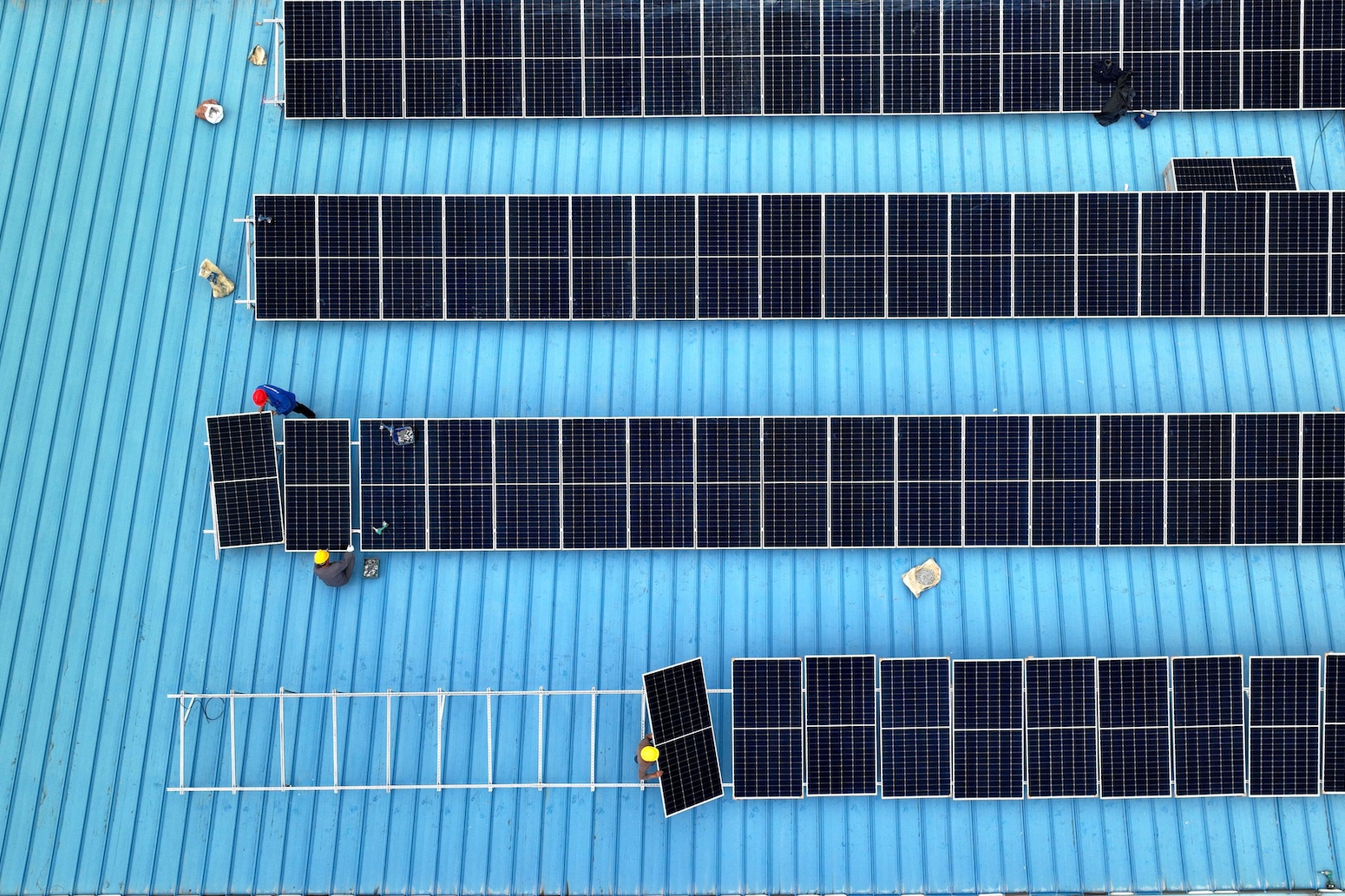 ** Workers installing solar panels on factory rooftop in Jiangsu province, China
