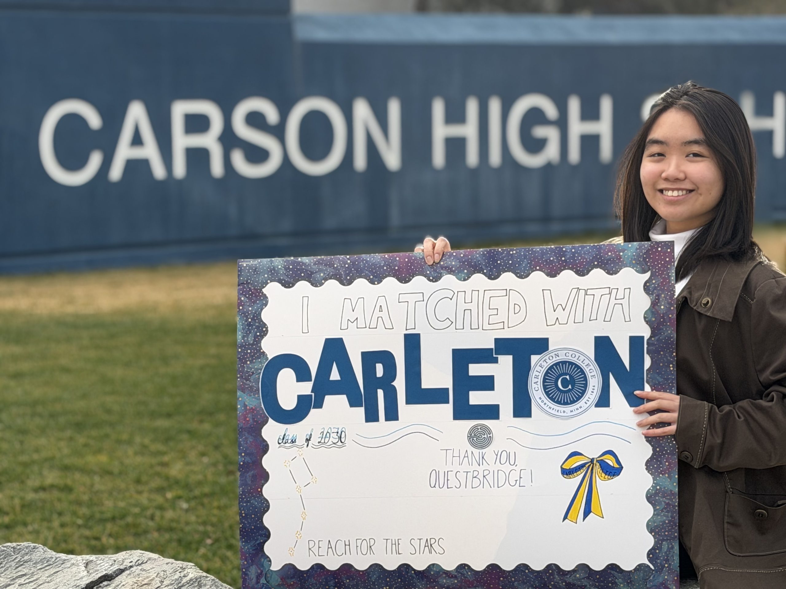 Female high school student in graduation cap smiling while holding acceptance letter and scholarship documents