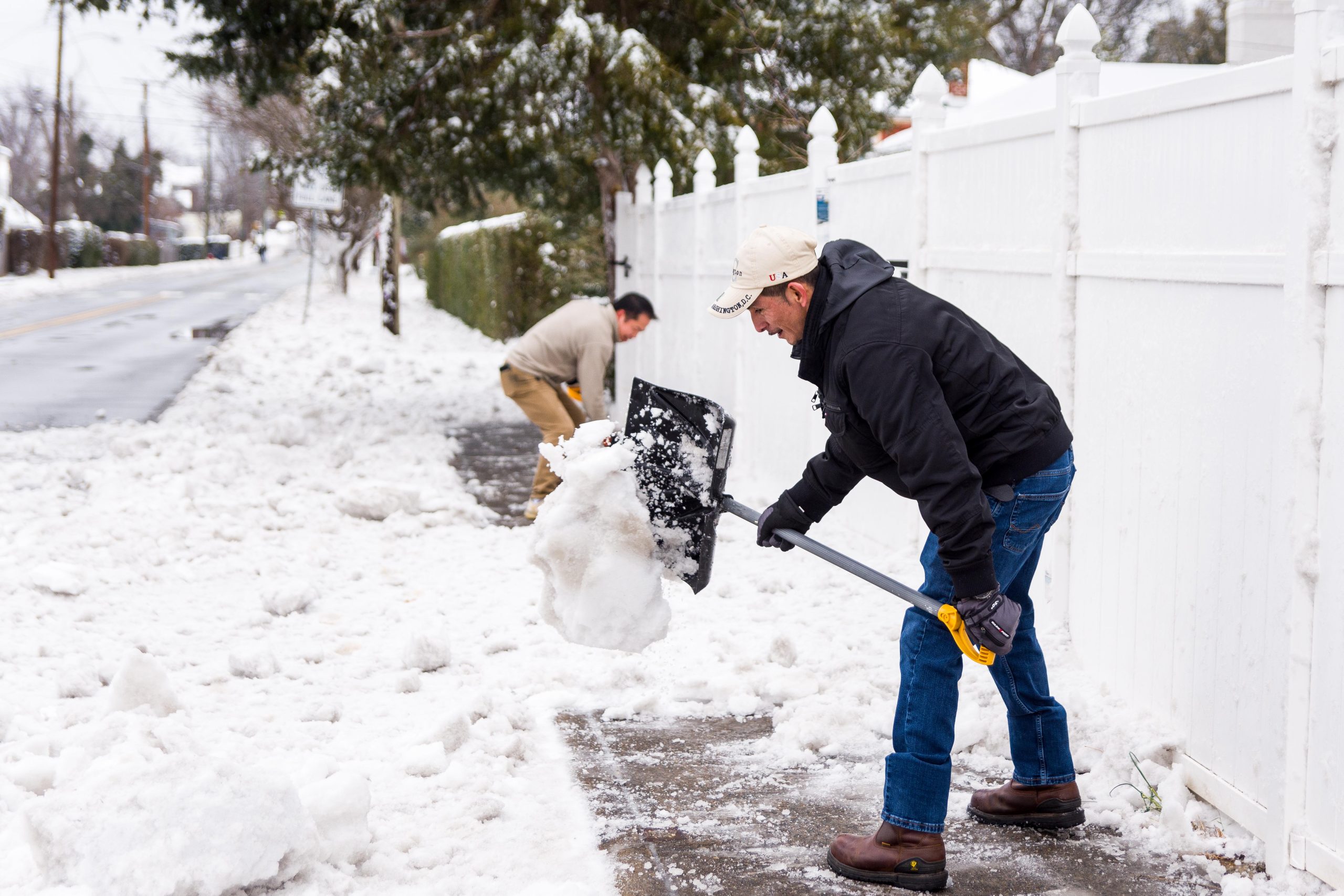 Volunteers shoveling snow from residential sidewalk in winter helping elderly neighbors stay safe