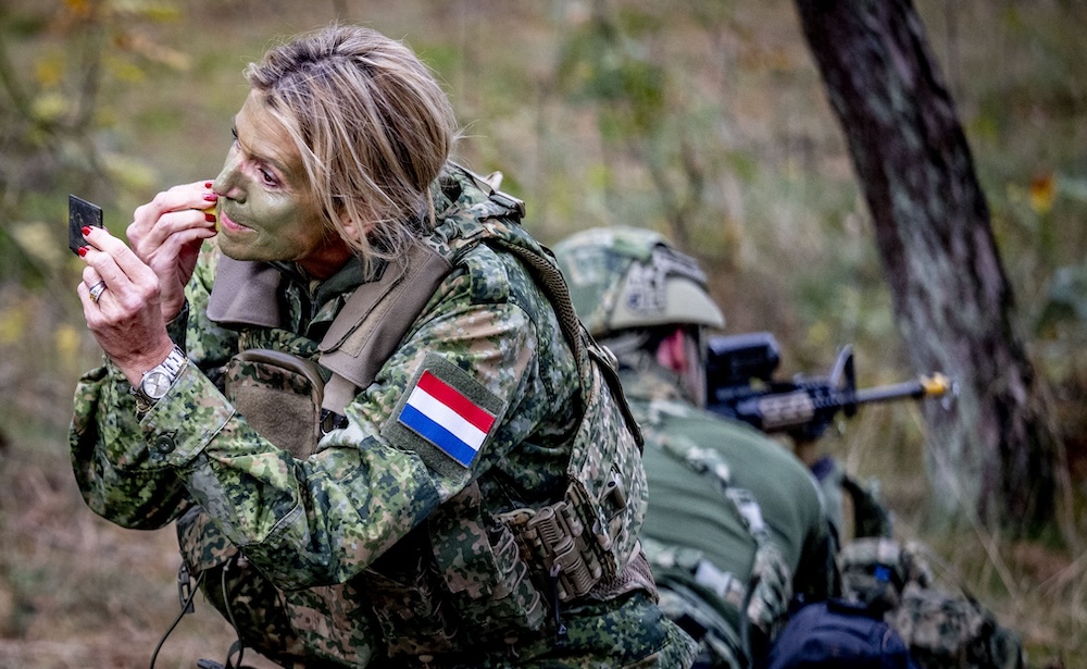 Queen Máxima applying camouflage face paint during visit to Dutch military police training center