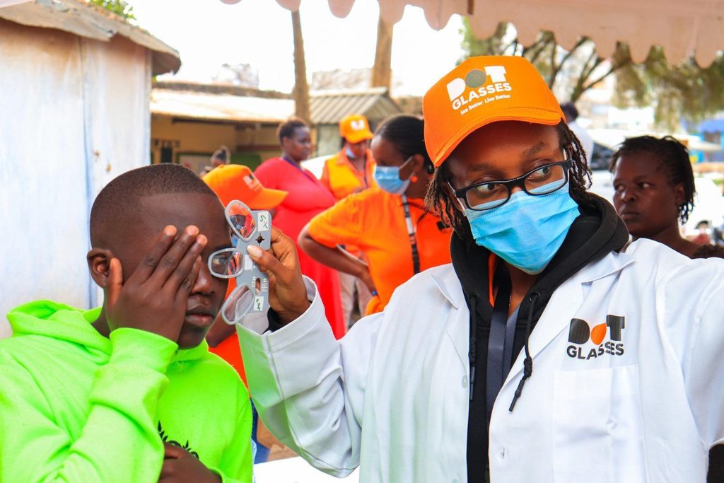 ** African entrepreneur assembling affordable custom eyeglasses for community member in Kenya