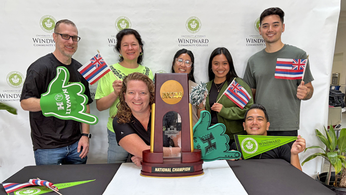 NCAA volleyball championship trophy on display at University of Hawaii campus with celebrating students