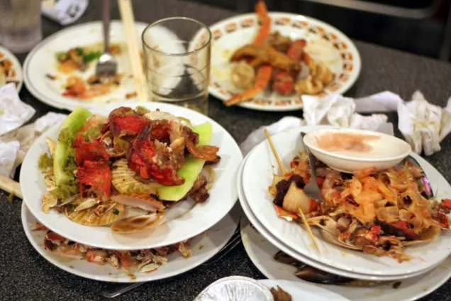 Restaurant kitchen staff preparing multiple plates of traditional Ghanaian food on serving counter