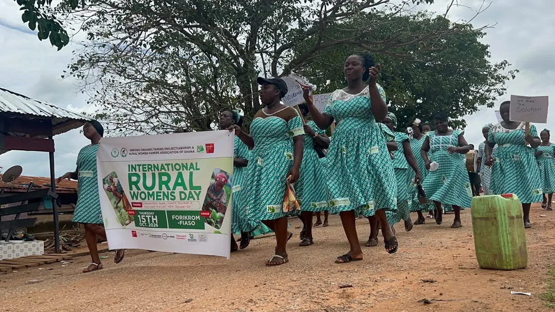 Ghanaian women farmers in colorful traditional dress marching with drums and placards celebrating rural women