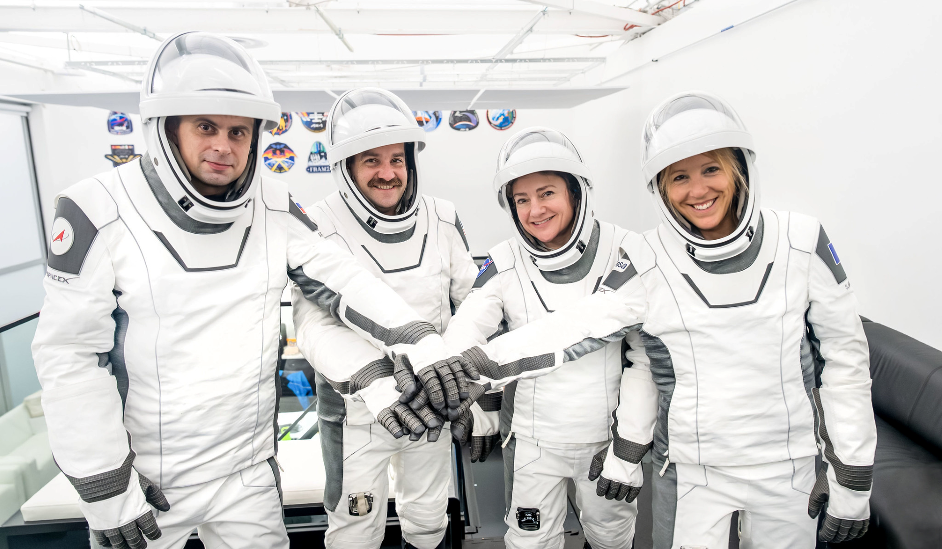 Four Crew-12 astronauts in blue flight suits standing together before space station mission