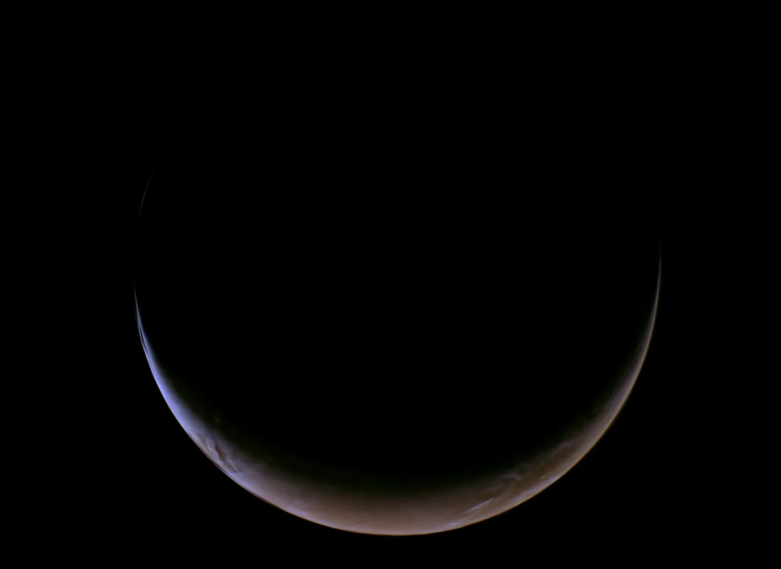 Crescent Mars glowing against black space captured by NASA's Psyche spacecraft during flyby