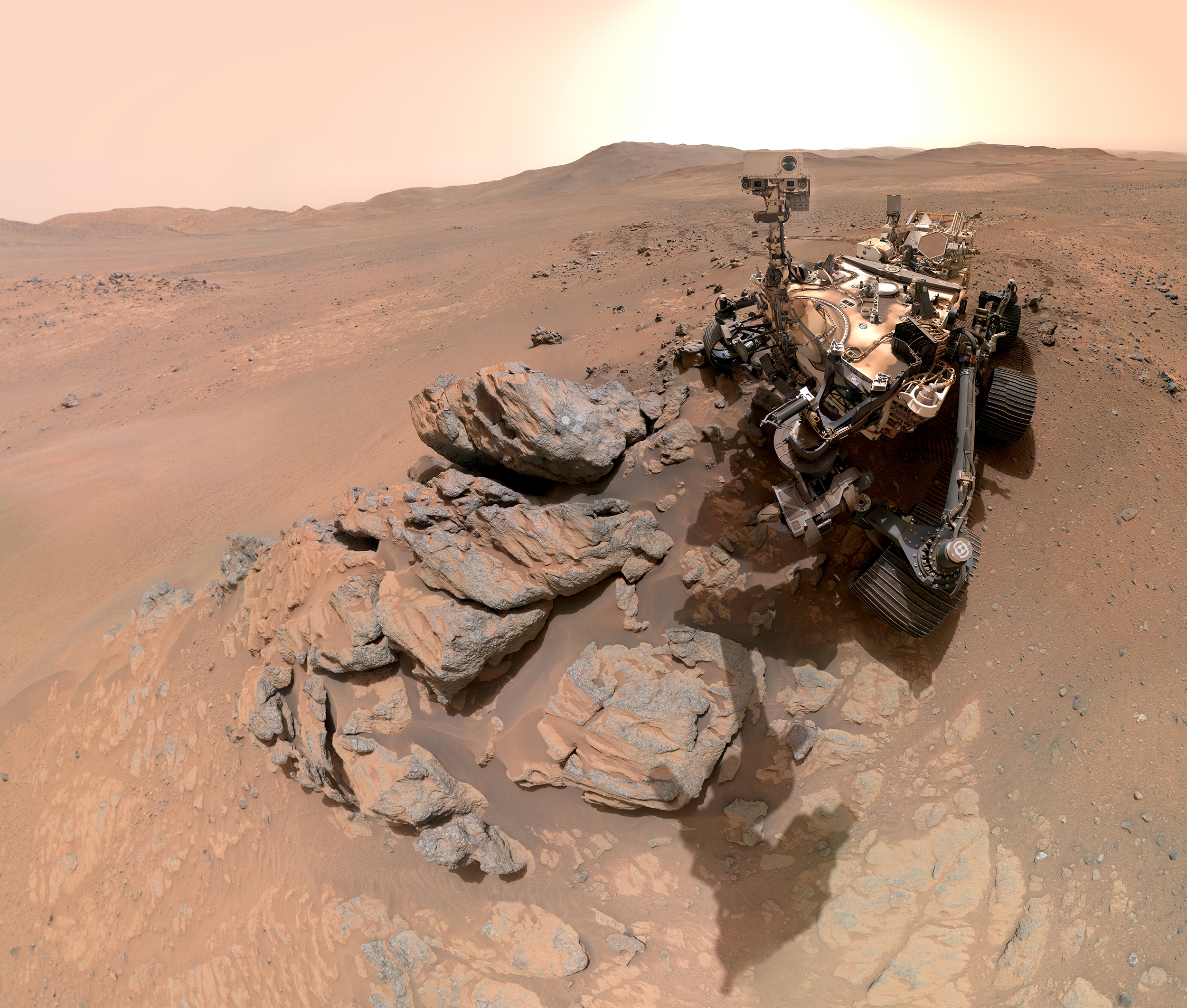 NASA Perseverance rover self-portrait showing robotic explorer analyzing rocks on Mars with crater rim background
