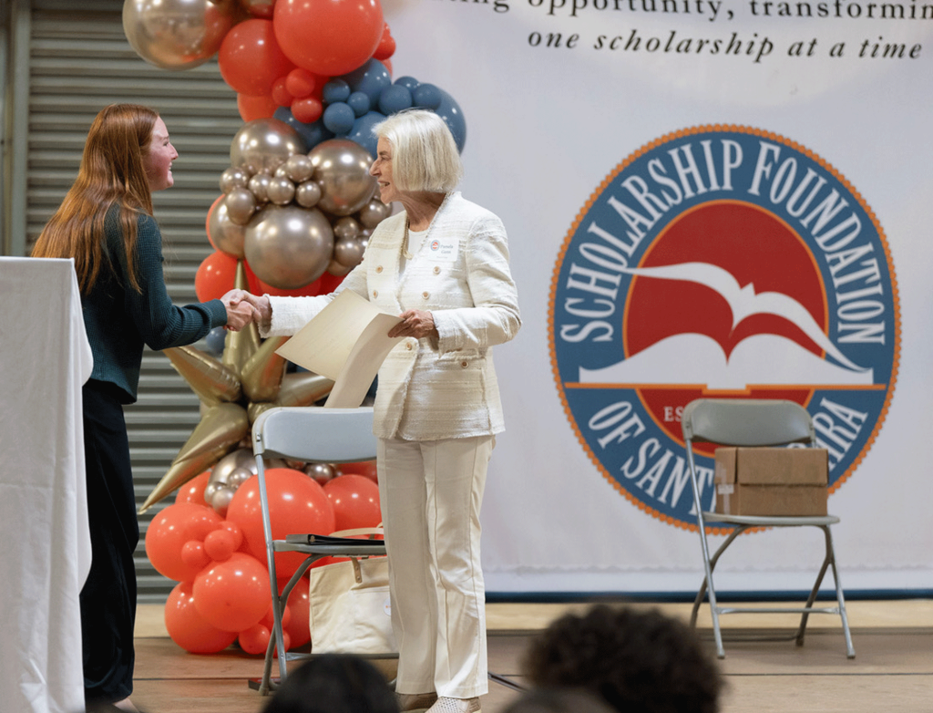 Scholarship Foundation Board Chair congratulates smiling student recipient at outdoor ceremony