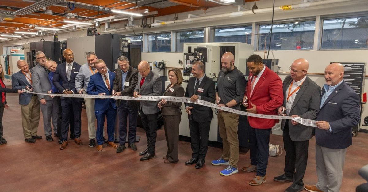 Modern manufacturing training facility interior with robotics equipment and students working alongside industry professionals