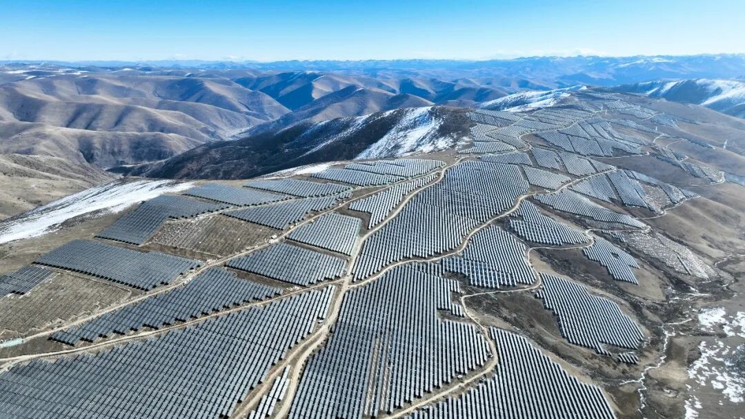 Vast solar panel array stretching across high altitude mountain plateau under bright blue sky