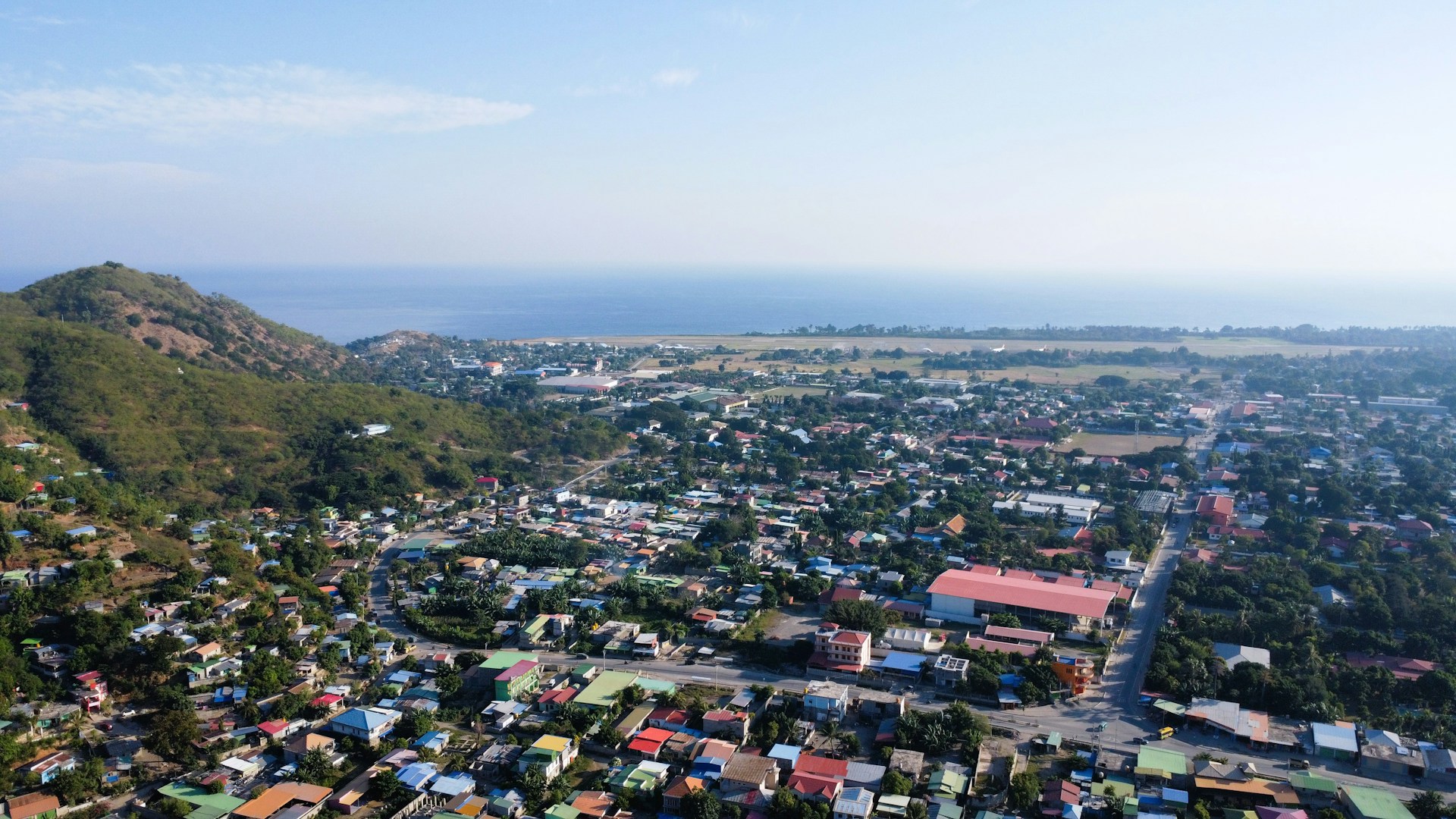 Solar panels stretching across landscape in Timor-Leste with battery storage facility under blue sky