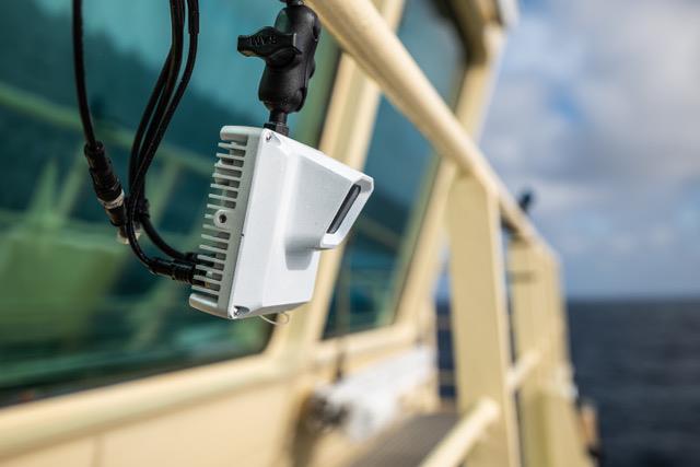 Compact AI camera mounted on sailing vessel railing to detect ocean plastic debris