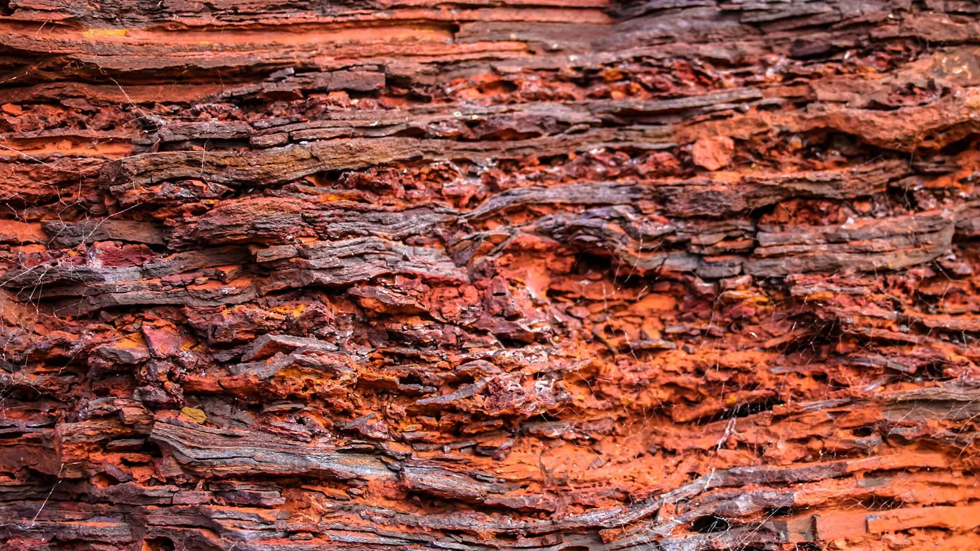 Red iron-rich rock formations in Western Australia's Pilbara region under blue sky