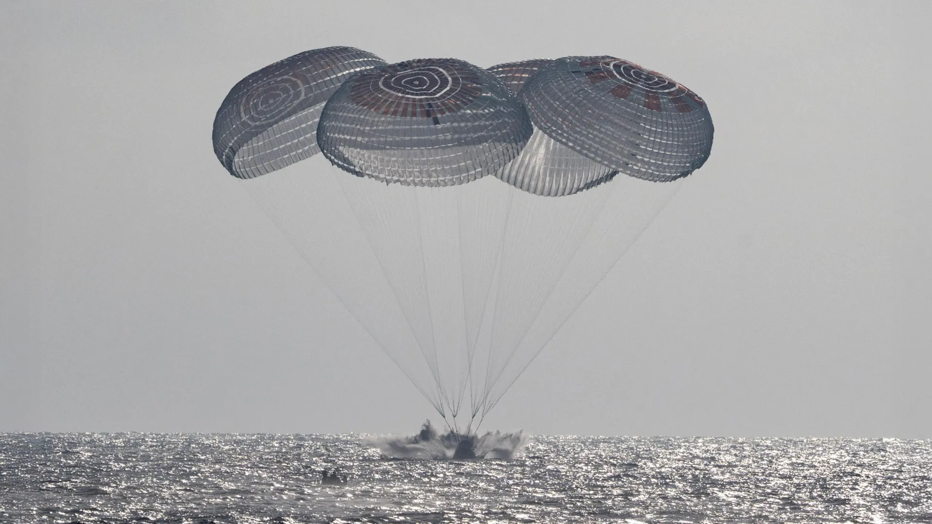 SpaceX Crew Dragon capsule floating in Pacific Ocean after splashdown with recovery team
