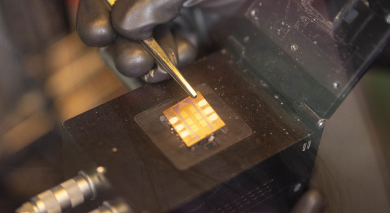 Researcher in white lab coat testing transparent organic solar cell panel in laboratory setting