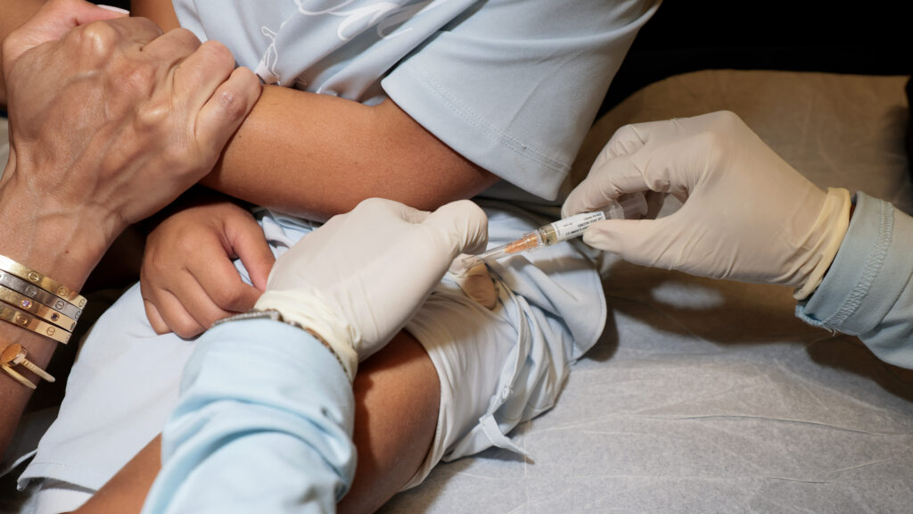 Pediatrician preparing vaccine dose in bright, modern children's hospital exam room