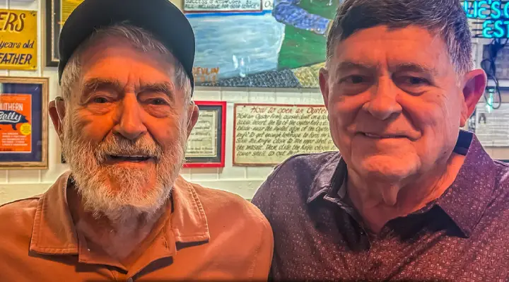Elderly father and 80-year-old son smiling together at oyster restaurant in Alabama