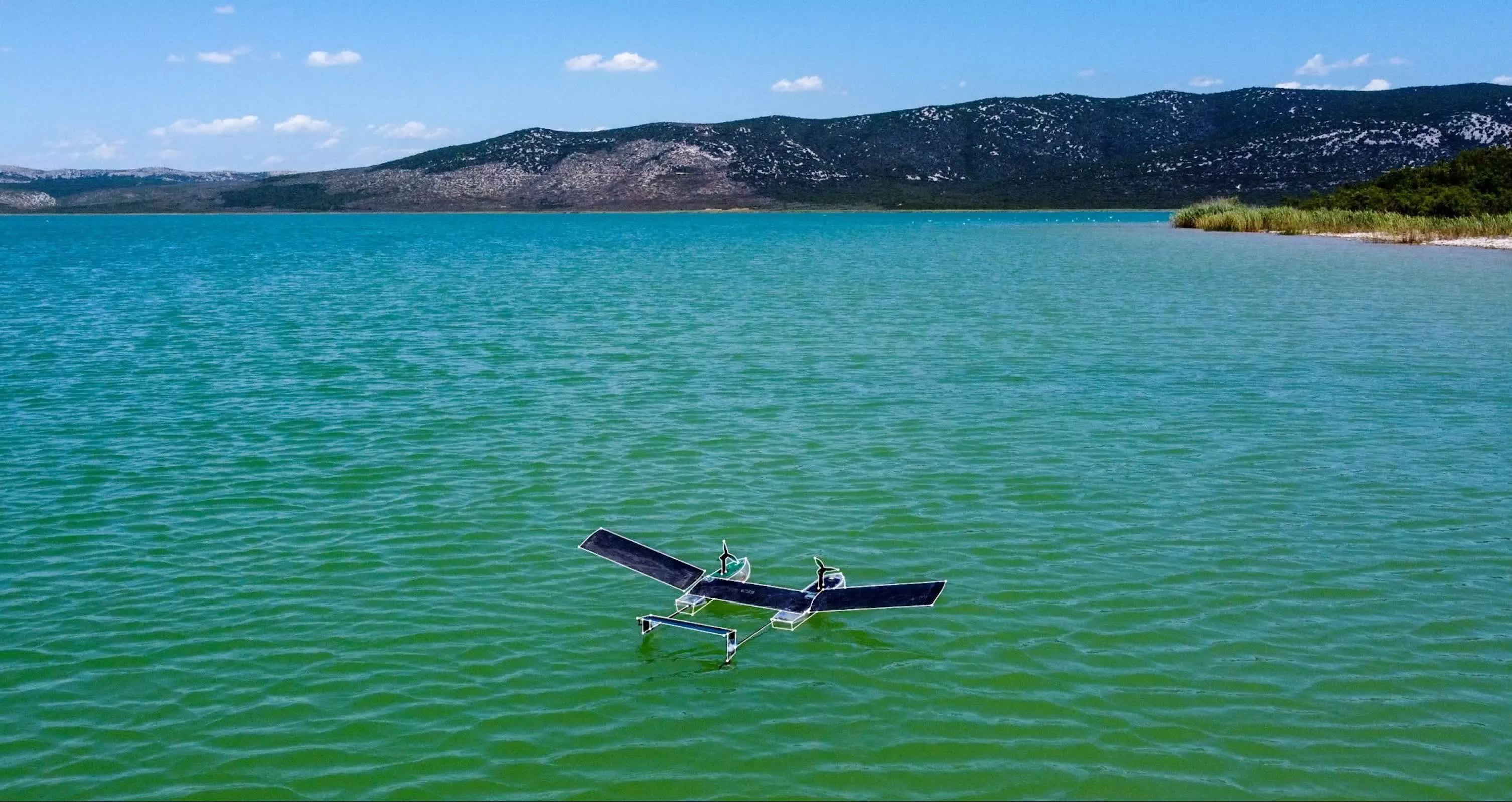 Small white winged robot with translucent wings breaking through water surface into flight