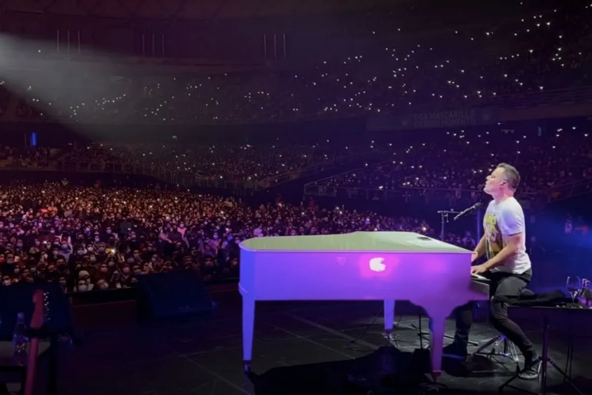 Marc Martel performing at piano with crowd of thousands singing along at concert