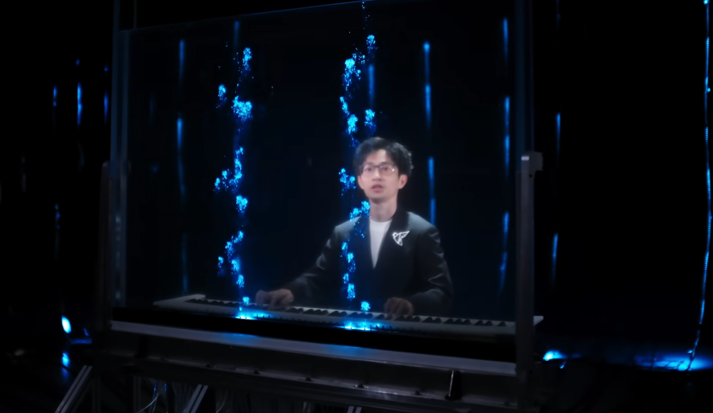 Piano with transparent tank filled with glowing blue bioluminescent algae above keyboard