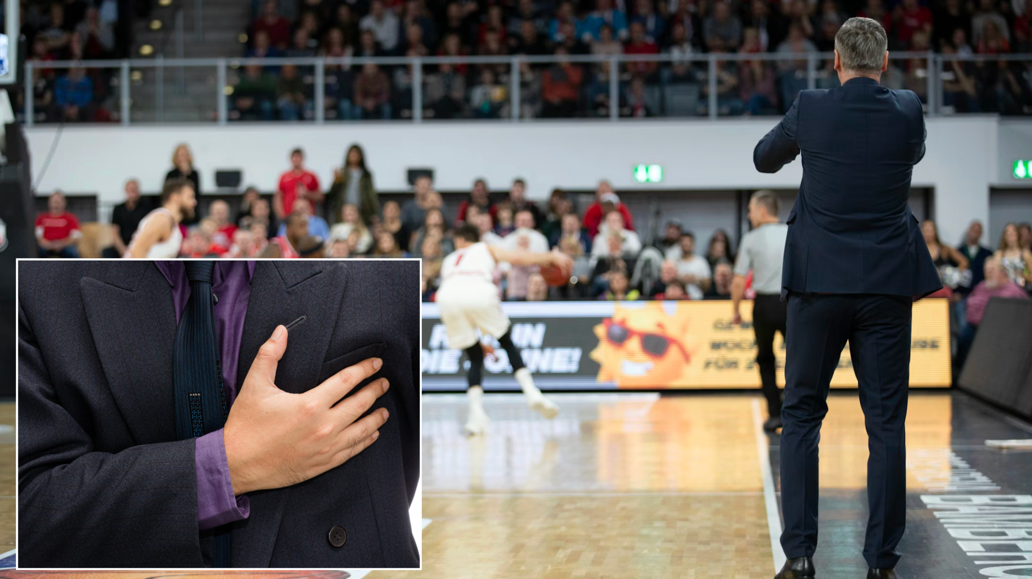 Basketball coach standing on sideline watching game in indoor gymnasium court