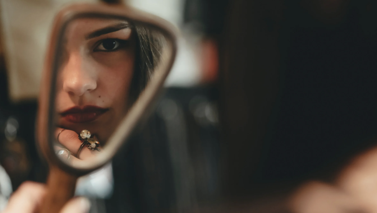 Young woman checking her swollen lip while looking concerned in a mirror