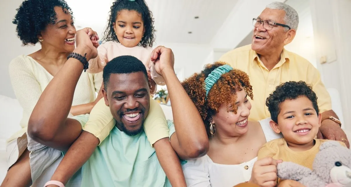 Three generations of family members smiling together in a comfortable living room
