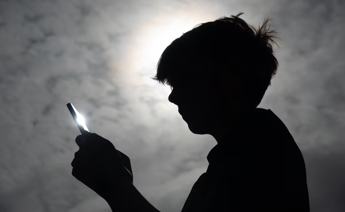 Parent and teenager looking at smartphone together discussing screen time limits and app settings