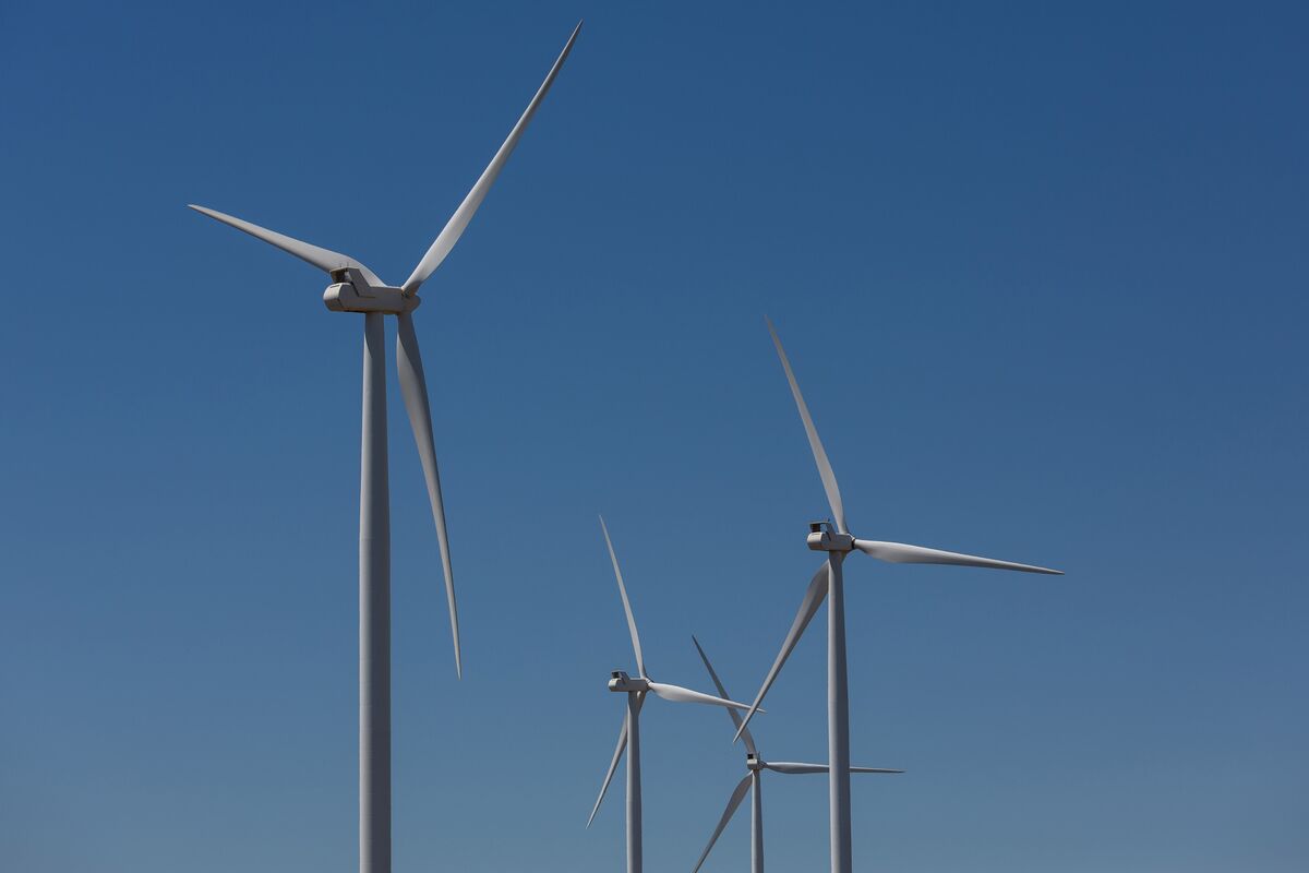 Wind turbines and solar panels against bright blue Australian sky with rolling landscape
