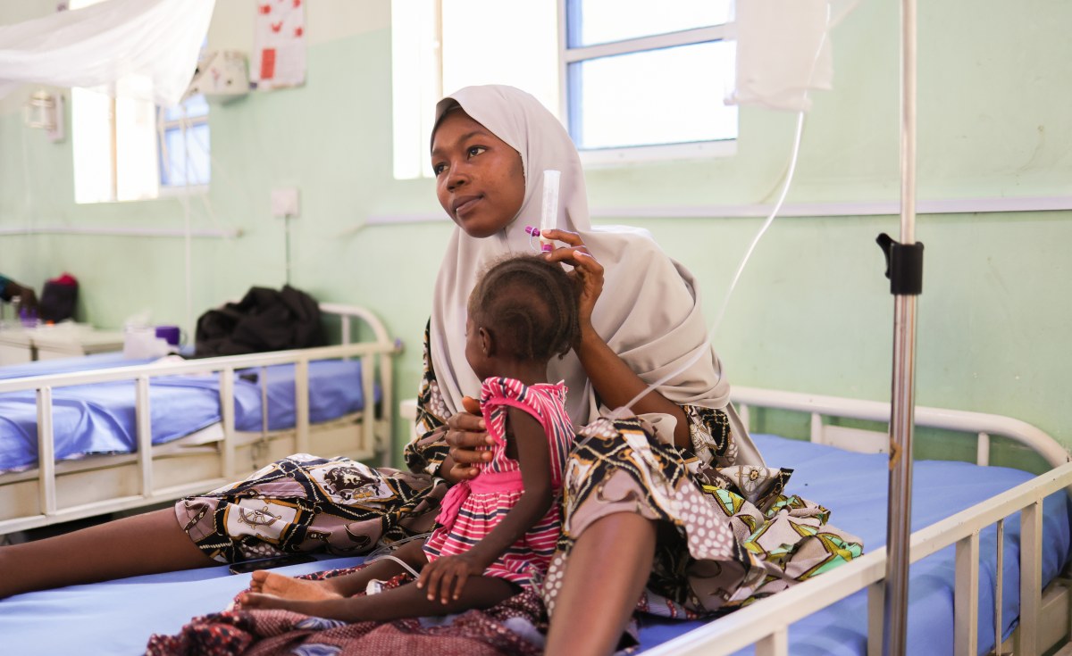 Mother sitting beside hospital bed caring for young child in Nigerian medical facility