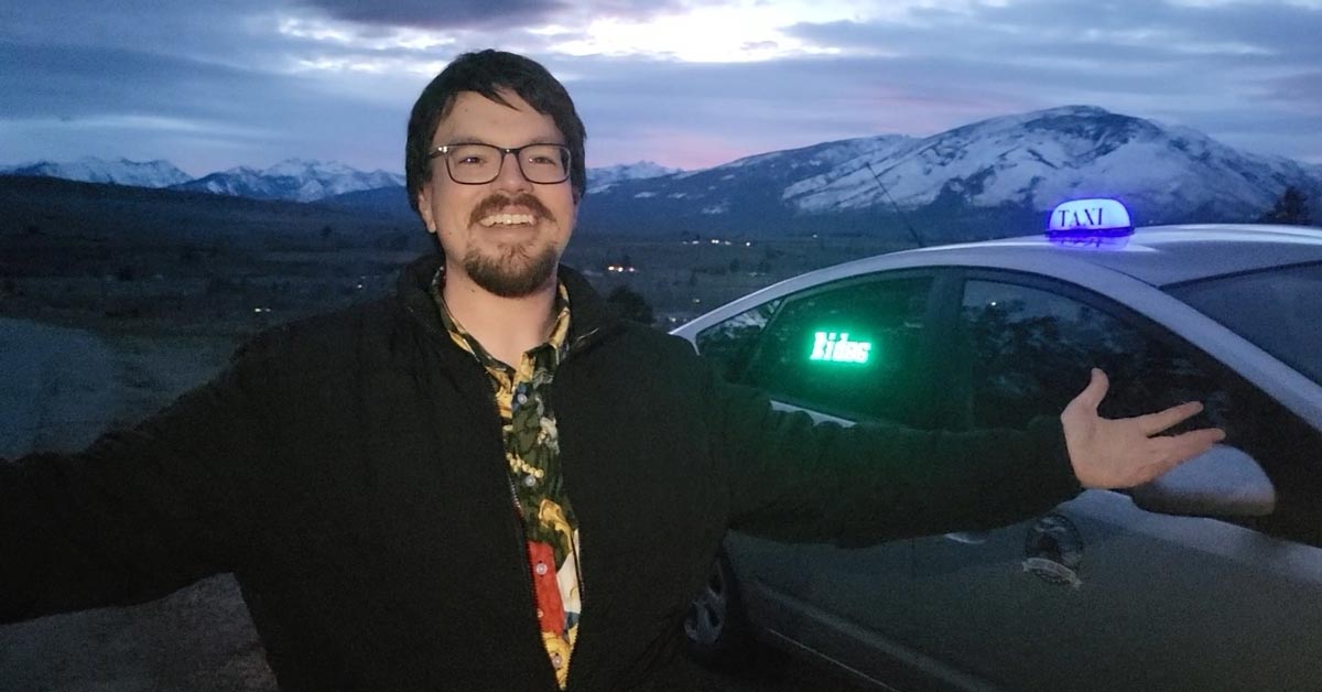 Daniel Foley standing beside vehicle smiling, founder of Giddy-Up Rides taxi service in Montana