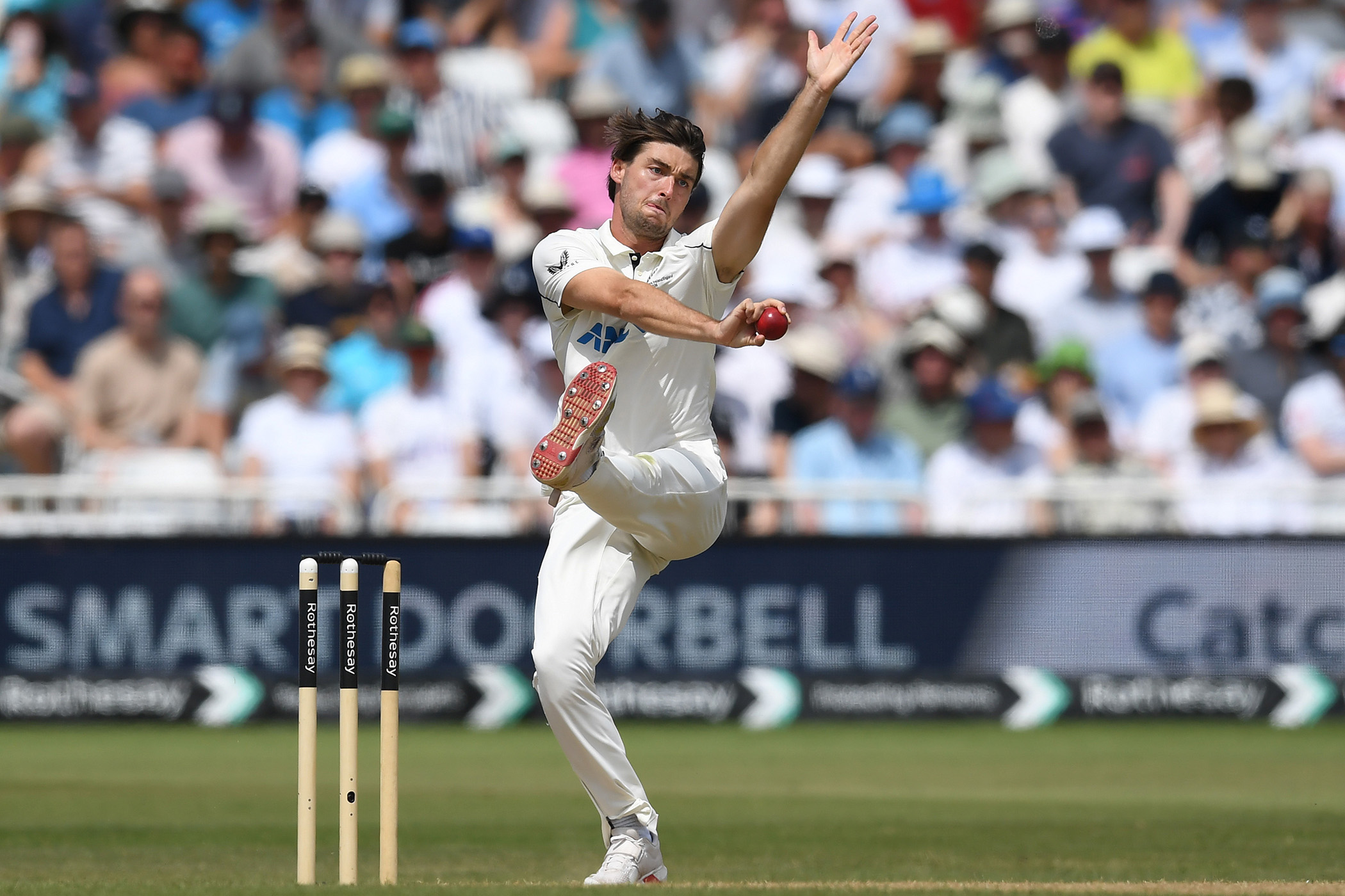 Cricket bowler Zak Foulkes in white uniform delivering ball at Trent Bridge stadium