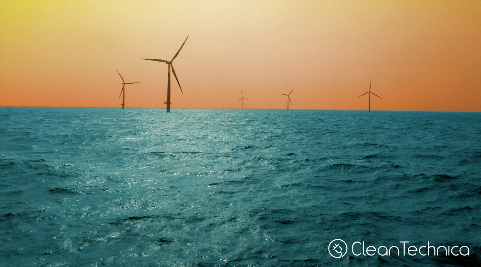 Offshore wind turbines rising from ocean waters along the Massachusetts coast at sunset