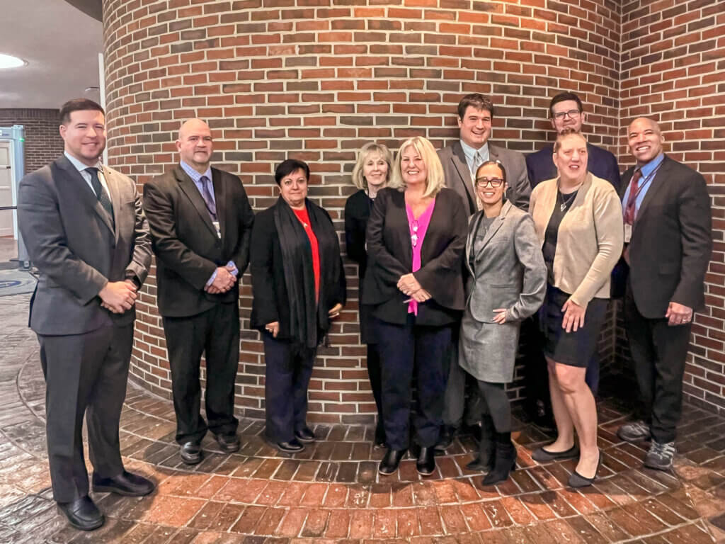 Court officials and staff standing together in courthouse celebrating mental health recovery program graduation