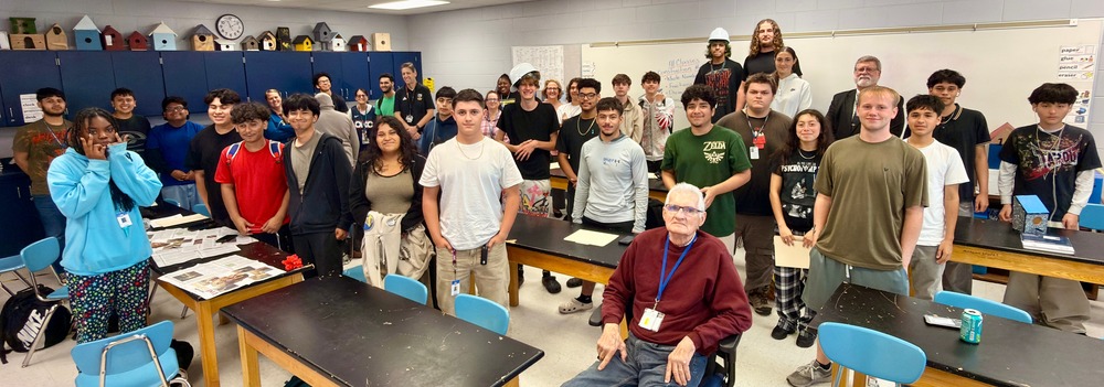 High school students wearing safety glasses working with construction tools in vocational training classroom