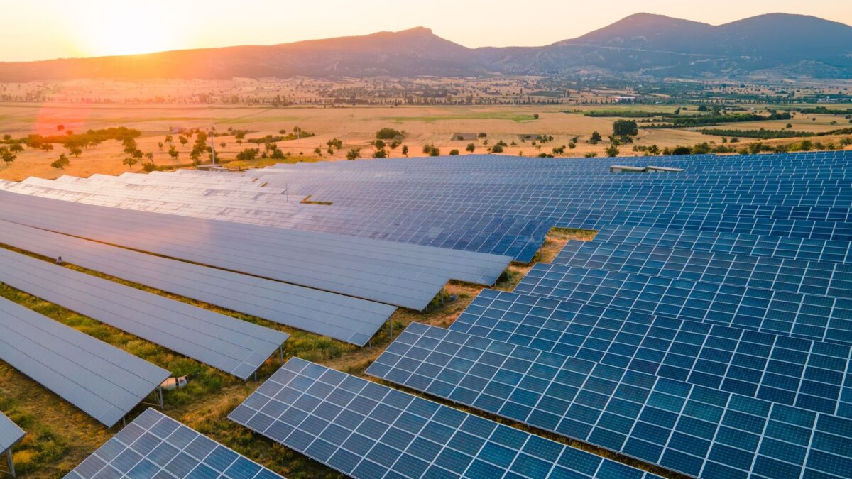 Wind turbines and solar panels in sunny field representing renewable energy solutions