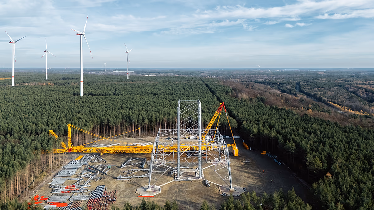 Massive lattice tower wind turbine under construction rising into blue sky in Brandenburg, Germany
