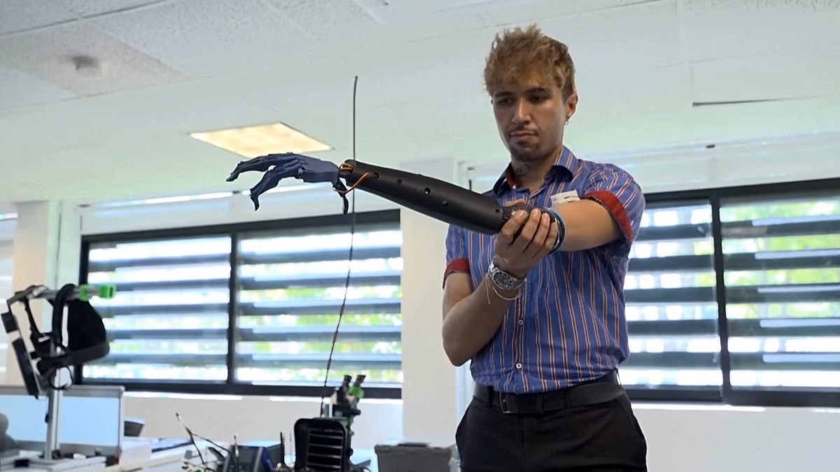 Person testing white 3D-printed prosthetic robotic arm with concealed motors in Guadalajara laboratory
