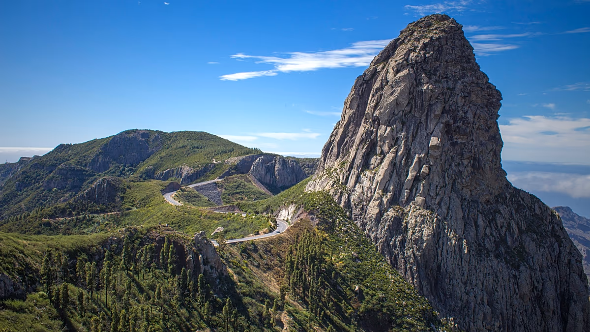 Hikers walking along dramatic volcanic cliffs overlooking the ocean on La Gomera island trail