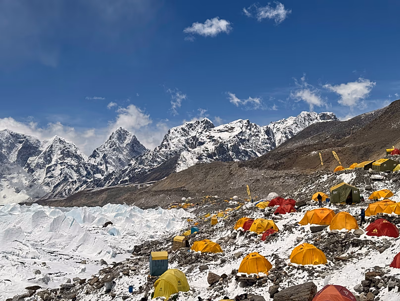 Mountain climbers ascending snowy slopes near Mount Everest summit with prayer flags