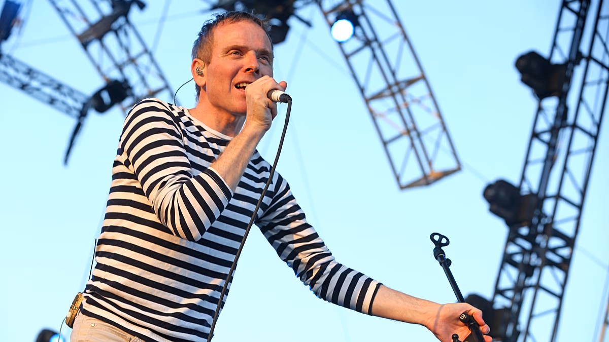 Belle and Sebastian band members performing with Scottish flag and football imagery in background