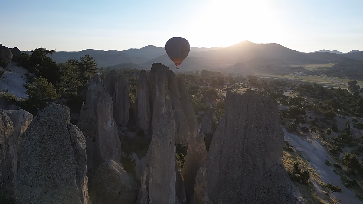 Hot air balloons floating over ancient Phrygian rock monuments in green valley landscape Turkey