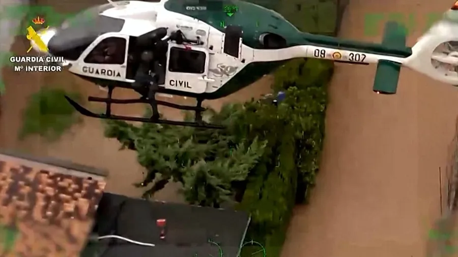 ** Guardia Civil officer carrying woman through floodwater during rescue operation in Oliva, Spain