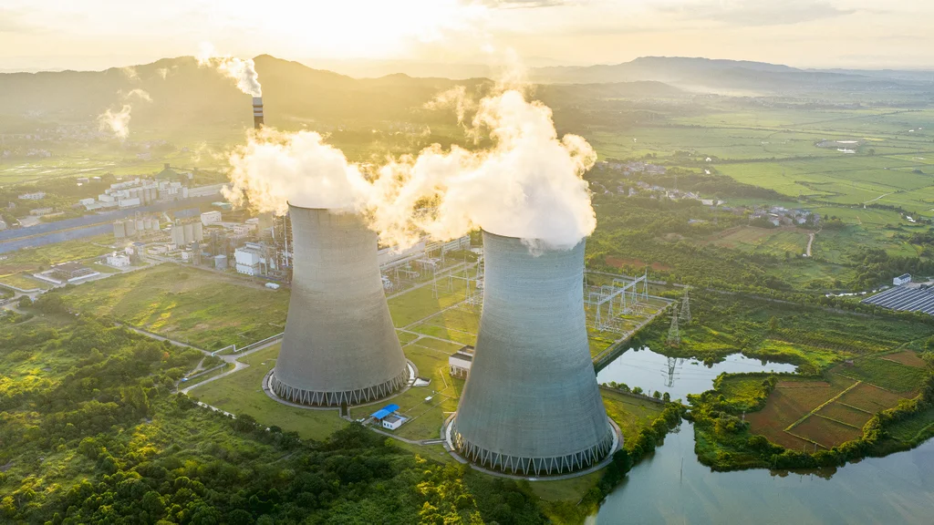 Modern nuclear power plant cooling towers with wind turbines and solar panels nearby