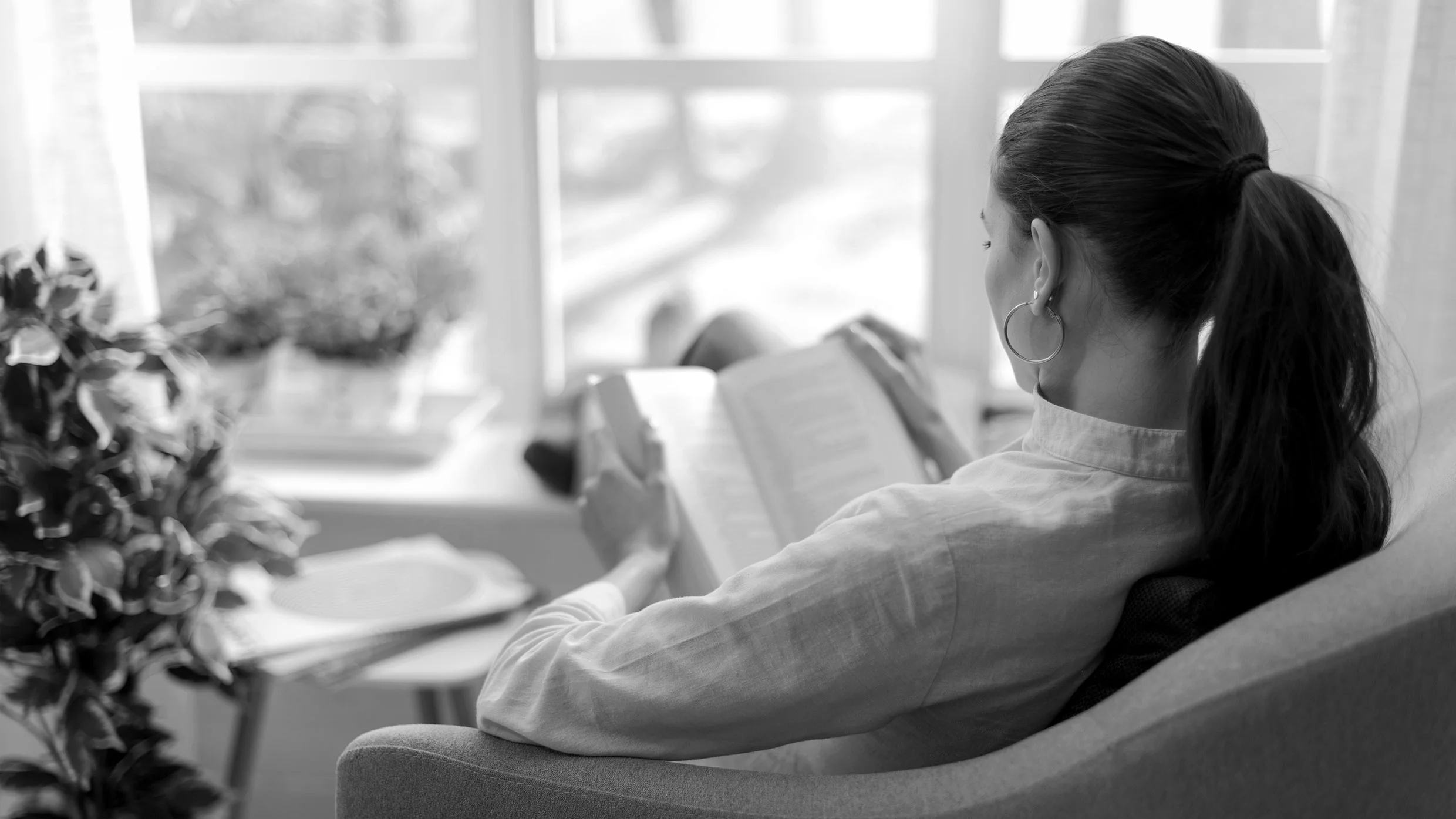 Person reading book peacefully in natural light, focused and engaged with content
