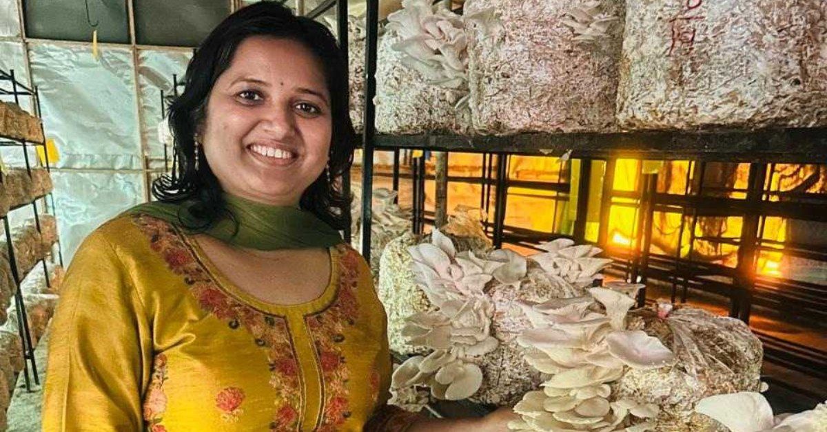 Trupti Dhakate standing in her mushroom farm holding fresh oyster mushrooms grown from agricultural waste