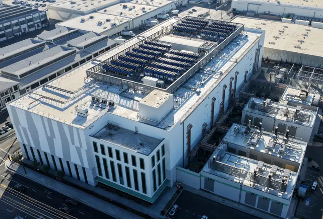Aerial view of modern data center facility surrounded by solar energy infrastructure in sunny desert landscape